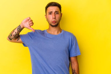 Sarı arka planda dövmeleri olan, hoşlanmadığı bir hareket gösteren beyaz, genç bir adam. Anlaşmazlık konsepti.