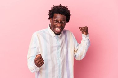 Genç Afrikalı Amerikalı adam pembe arka planda izole edilmiş tasasız ve heyecanlı bir şekilde tezahürat yapıyor. Zafer konsepti.