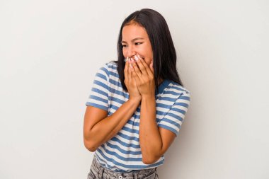 Beyaz arka planda izole edilmiş genç Latin bir kadın bir şeye gülüyor, elleriyle ağzını kapatıyor..