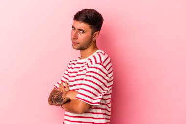 Sarı arka planda izole edilmiş dövmeleri olan beyaz bir genç şüpheli, belirsiz, seni muayene ediyor..