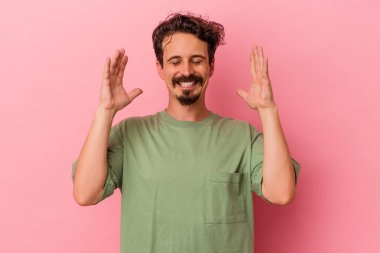 Pembe arka planda izole edilmiş genç beyaz bir adam neşeli bir şekilde gülüyor. Mutluluk kavramı.