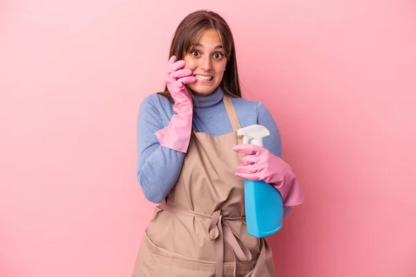 Junge Kaukasische Putzfrau Hält Spray Isoliert Auf Rosa Hintergrund Beißt — Stockfoto