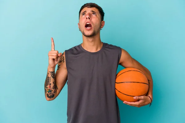 Молодой Кавказский Мужчина Играет Баскетбол Синем Фоне Указывая Вверх Ногами — стоковое фото