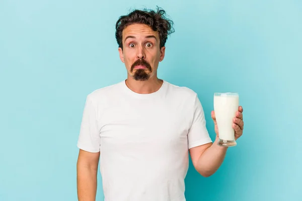 Young Caucasian Man Holding Glass Milk Isolated Blue Background Shrugs — Fotografia de Stock