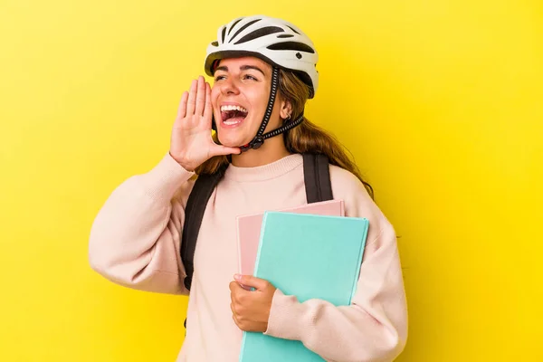 若いですCaucasian学生女性身に着けていますAバイクヘルメット隔離上の黄色の背景叫びと保持手のひら近くにオープン口 — ストック写真