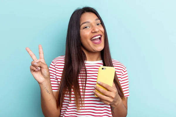 Ung Venezuelansk Kvinna Som Håller Mobiltelefon Isolerad Blå Bakgrund Glad — Stockfoto