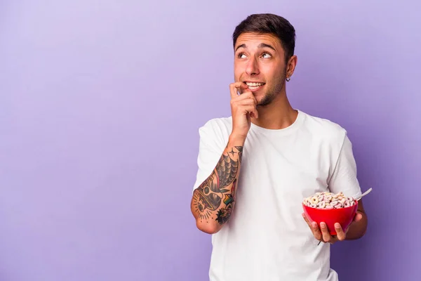 Joven Hombre Caucásico Comiendo Cereales Aislados Sobre Fondo Púrpura Relajado — Foto de Stock