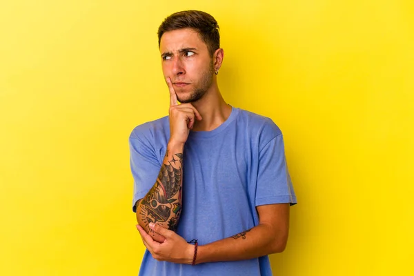 Young Caucasian Man Tattoos Isolated Yellow Background Looking Sideways Doubtful — 스톡 사진