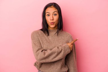 Pembe arka planda izole edilmiş genç Latin kadın yan tarafı gösteriyor.