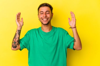 Sarı arka planda izole edilmiş dövmeleri olan, neşeli gülüşlü beyaz bir genç. Mutluluk kavramı.