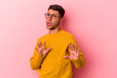 Sarı arka planda dövmeleri olan beyaz bir genç adam tiksinti belirtisi gösteren birini reddediyor..