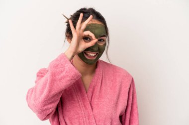 Young caucasian woman wearing a facial mask isolated on white background excited keeping ok gesture on eye.