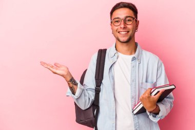 Pembe arka planda izole edilmiş kitapları tutan beyaz bir öğrenci bir avuç içinin fotokopi çektiğini ve başka bir elini belinde tuttuğunu gösteriyor..