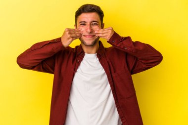 Sarı arka planda dövmeleri olan beyaz bir adam iki seçenek arasında kuşkulanıyor..