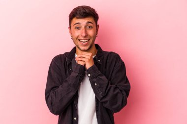 Sarı arka planda izole edilmiş beyaz dövmeli genç bir adam şans için dua ediyor, şaşırıyor ve ağzını açıyor..