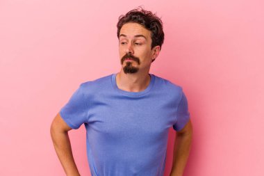 Pembe arka planda izole edilmiş genç beyaz adam hedeflere ve amaçlara ulaşma hayali kuruyor.