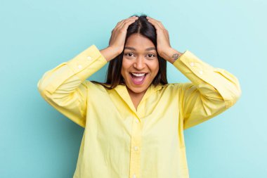 Genç Venezuelalı bir kadın mavi arka planda izole edilmiş bağırıyor, çok heyecanlı, tutkulu, bir şeyden memnun..