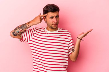 Sarı arka planda dövmeleri olan beyaz genç bir adam işaret parmağıyla yaptığı hayal kırıklığını gösteriyor..