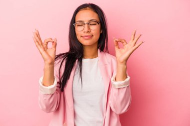 Pembe arka planda izole edilmiş genç Latin kadın sıkı çalışma gününden sonra dinleniyor, yoga yapıyor..