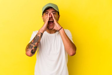 Sarı arka planda izole edilmiş dövmeleri olan beyaz bir genç öne doğru heyecanlı bağırıyor..