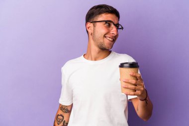 Elinde mor arka planda izole edilmiş kahve taşıyan beyaz bir adam gülümsüyor, neşeli ve keyifli görünüyor..