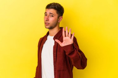 Sarı arka planda dövmeleri olan beyaz bir genç adam tiksinti belirtisi gösteren birini reddediyor..