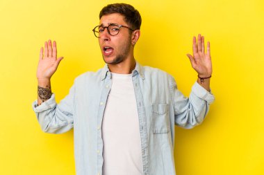 Sarı arka planda dövmeleri olan beyaz bir genç yakın bir tehlike nedeniyle şoka uğruyor.