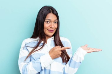 Venezuelalı genç bir kadın mavi arka planda izole edilmiş..
