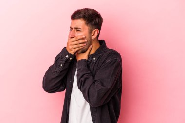 Sarı arka planda dövmeleri olan beyaz genç bir adam virüs ya da enfeksiyon yüzünden boğazında ağrı hissediyor..