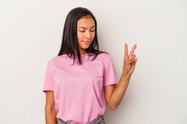 Beyaz arka planda izole edilmiş genç Latin kadın neşeli ve kaygısız parmakları olan bir barış sembolü gösteriyor..