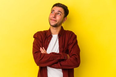 Sarı arka planda izole edilmiş dövmeleri olan genç beyaz adam amaçlarına ve amaçlarına ulaşmayı hayal ediyor.