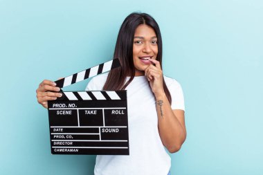 Genç Venezüellalı bir kadın mavi arka planda izole edilmiş bir klasör tutuyor. Bir şeyin fotokopi odasına baktığını düşünerek rahatlıyor..