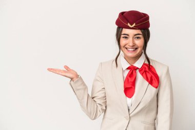 Young caucasian stewardess woman isolated on white background showing a copy space on a palm and holding another hand on waist.
