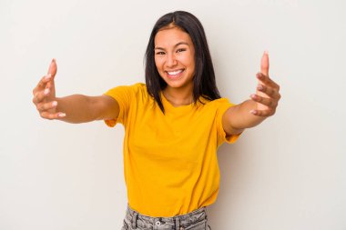 Beyaz arka planda izole edilmiş genç Latin bir kadın zaferi ya da başarıyı kutluyor, şaşırıyor ve şok oluyor..