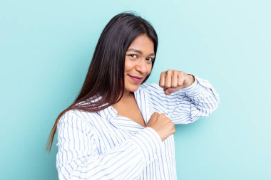 Genç Venezuelalı bir kadın mavi arka planda izole edilmiş. Bir tartışma yüzünden yumruk, öfke ve kavga atıyor..