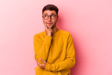 Sarı arka planda izole edilmiş dövmeleri olan genç, beyaz bir adam. Bir strateji planlıyor, bir işin nasıl olacağını düşünüyor..