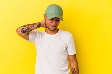 Sarı arka planda izole edilmiş beyaz dövmeli genç bir adam sabit yaşam tarzından dolayı boyun ağrısı çekiyor..