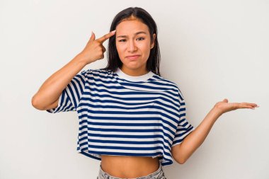 Beyaz arka planda izole edilmiş genç Latin kadın elinde bir ürün tutuyor ve.