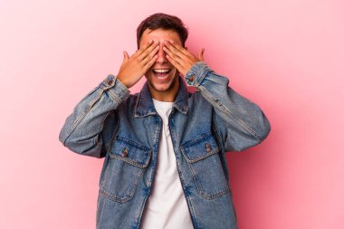 Sarı arka planda izole edilmiş dövmeleri olan genç, beyaz bir adam. Gözleri ellerle kaplıyor. Gülümsüyor ve bir sürpriz bekliyor..