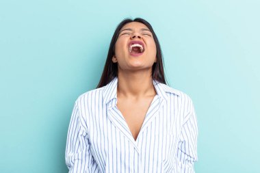 Genç Venezuelalı bir kadın mavi arka planda izole edilmiş çok kızgın, öfkeli, hayal kırıklığına uğramış bağırıyor..