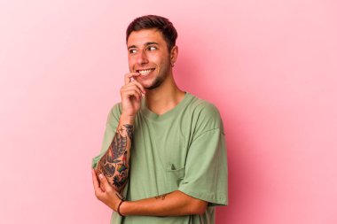 Sarı arka planda izole edilmiş beyaz dövmeli genç bir adam. Bir şeyin fotokopi odasına baktığını düşünerek rahatlamış..