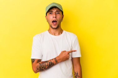 Sarı arka planda izole edilmiş dövmeleri olan genç, beyaz bir adam.