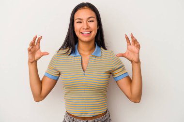 Beyaz arka planda izole edilmiş genç Latin bir kadın elinde avuç içi bir şeyle kameraya sunuyor..