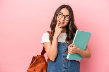 Young caucasian student woman isolated on pink background relaxed thinking about something looking at a copy space.