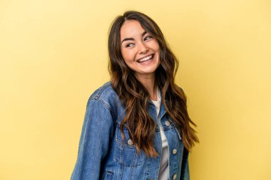 Sarı arka planda izole edilmiş genç beyaz kadın gülüyor ve gözlerini kapıyor, rahatlamış ve mutlu hissediyor..