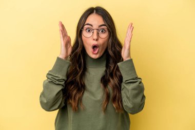 Sarı arka planda izole edilmiş genç beyaz kadın şaşırdı ve şok oldu..