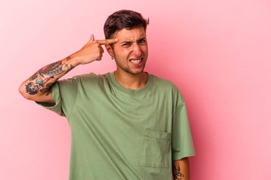 Sarı arka planda dövmeleri olan beyaz genç bir adam işaret parmağıyla yaptığı hayal kırıklığını gösteriyor..