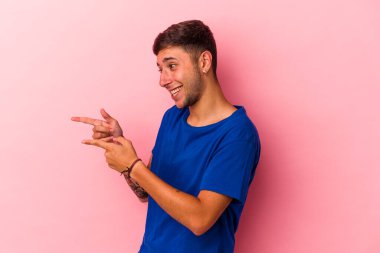 Sarı arka planda dövmeleri olan genç beyaz bir adam. Baş parmak uzakta, gülüyor ve kaygısız..