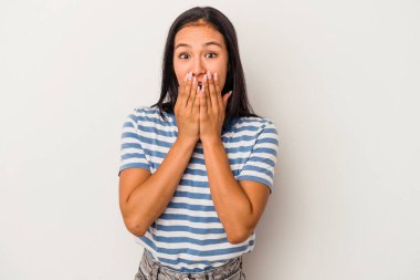 Beyaz arka planda izole edilmiş genç Latin kadın elleriyle ağzını kapatırken şok oldu..