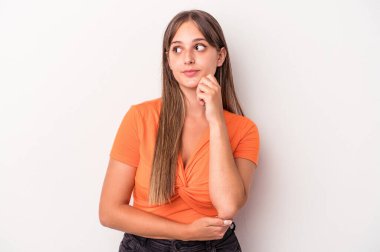 Beyaz arka planda soyutlanmış beyaz tenli genç bir kadın şüpheli ve şüpheci bir ifadeyle yana bakıyor..